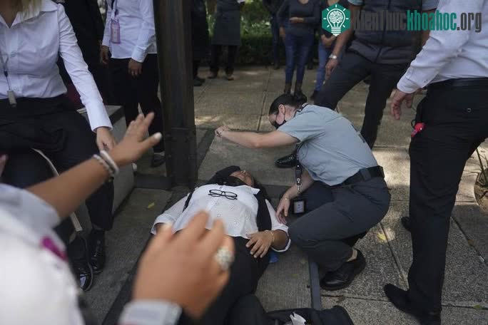 Một phụ nữ ở Mexico City được hỗ trợ giữa lúc mọi người tụ tập bên ngoài vì động đất