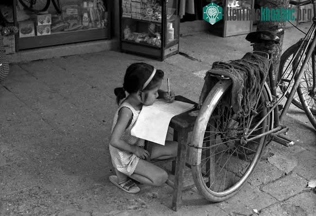 Bé gái tập viết trên vỉa hè phố cổ.