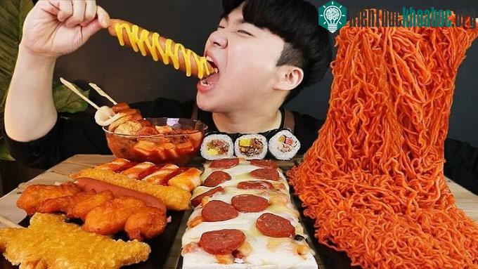 Một người ăn lượng lớn thức ăn trong khi tự quay camera và tương tác trực tiếp với người xem.