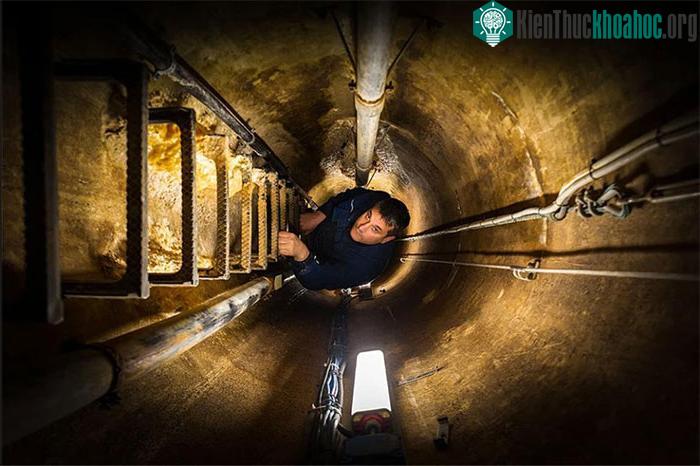 Một thợ điện đang đi xuống hệ thống đường hầm trong ca làm việc
