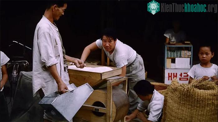 Người bán gạo bên cạnh chiếc máy xát gạo của mình