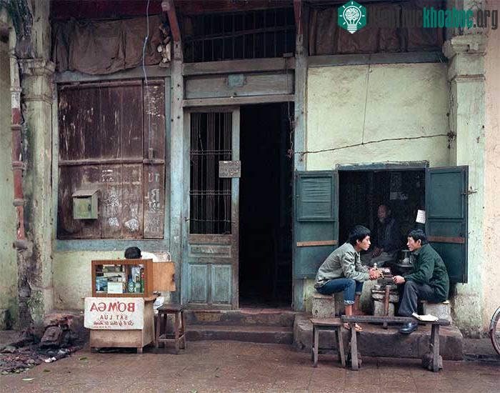 Cảnh hai người đàn ông uống nước chè, bên cạnh là quầy bơm ga bật lửa