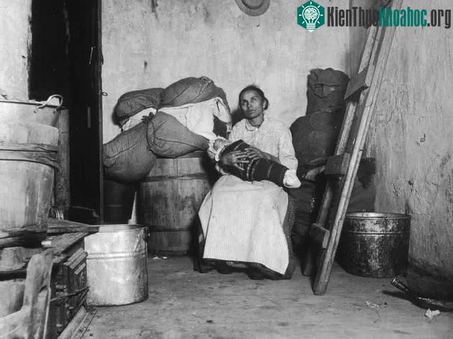 Một người Ý nhập cư ngồi ôm con trong một căn phòng chung cư nhỏ xuống cấp