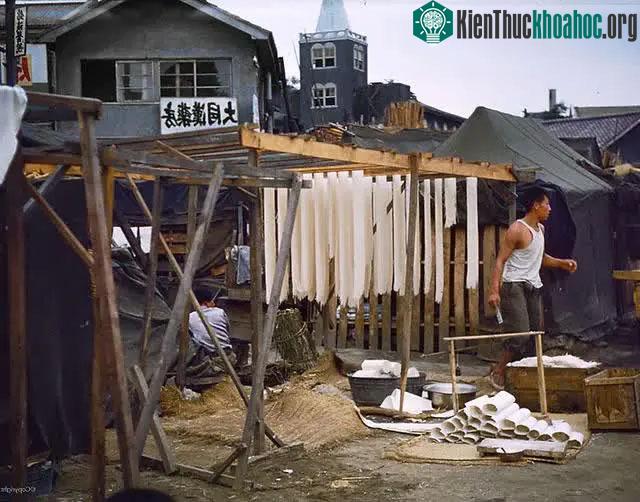 Một người làm mỳ thủ công trên phố với những giá phơi khô đơn giản và rơm rạ phía dưới