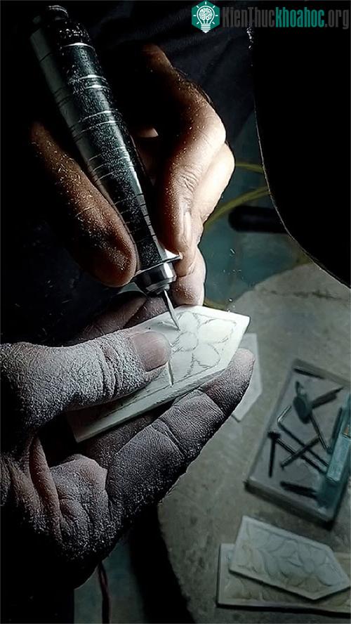 Người nghệ nhân đang chạm khắc trên một mảnh xương.