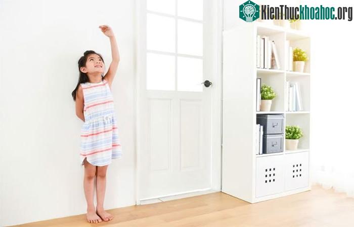 Một bé gái dùng tay để đo chiều cao của mình