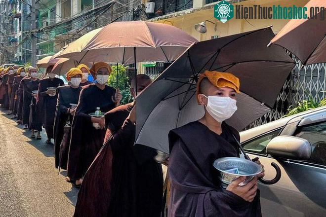 Các nữ tu đi khất thực với khăn trùm đầu và che ô để tránh nắng