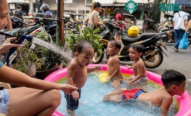 Đám trẻ chơi trong bể bơi bơm hơi bên đường
