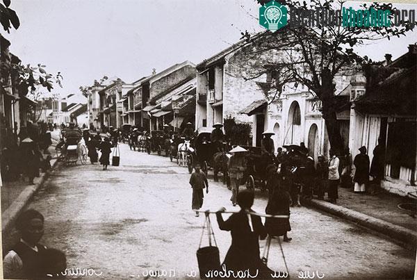 Phố Hàng Than năm 1951 có nhiều xe ngựa, xích lô và phụ nữ quảy quang gánh tấp nập.