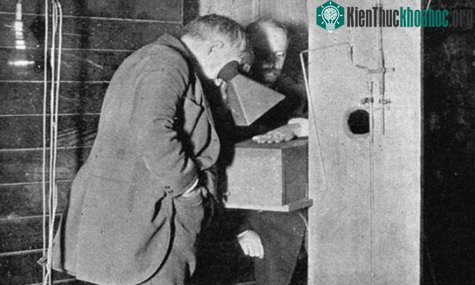 Edison nhòm qua kính huỳnh quang để quan sát bàn tay của Dally dưới tia X.