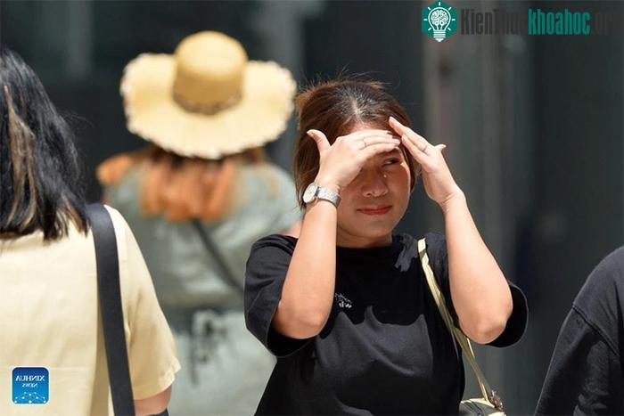 Một người đi bộ lấy tay che nắng khi đi ở Bangkok, Thái Lan
