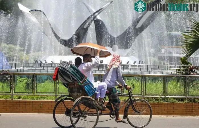 Một chiếc xe kéo đi ngang qua đài phun nước trong đợt nắng nóng đang diễn ra ở Bangladesh