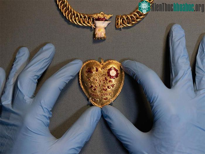 &nbsp;&nbsp;Mặt dây chuyền có biểu tượng hoa hồng Tudor màu đỏ và trắng, nằm giữa bụi cây lựu.