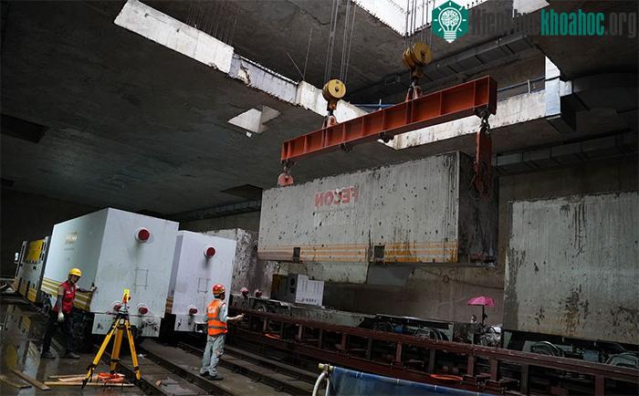 Các thùng chứa đất thải được cần cẩu đưa lên mặt đất và đổ xuống một bể chứa