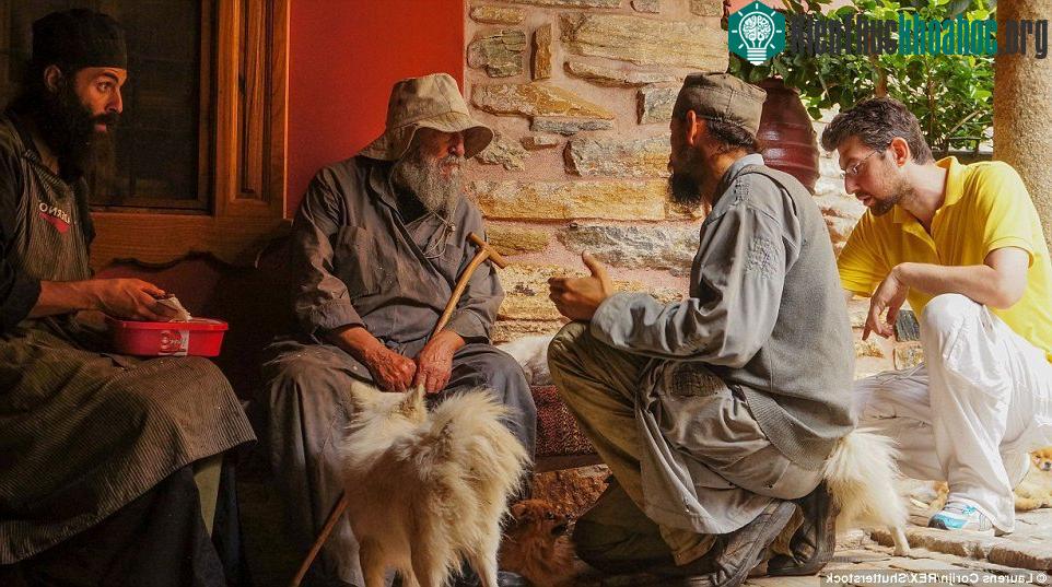Các tu sĩ trẻ và một công nhân ngồi quanh thầy tu lớn tuổi ngoài tu viện Dochiariou.