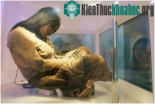 Cô bé ngồi với tư thế hai chân gập cong, tay để trước bụng.