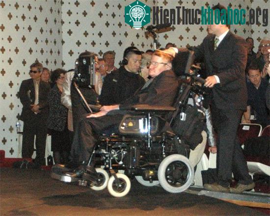 Stephen Hawking được trợ giúp đưa lên sân khấu thuyết trình bài “Nguồn gốc của vũ trụ”. (Ảnh:&nbsp;livescience.com)