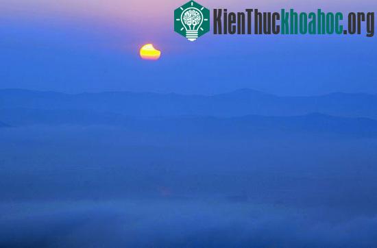 Mặt trời bị che lấp một phần dần dần lặn xuống phía sau các dãy núi mờ sương tại Changchun