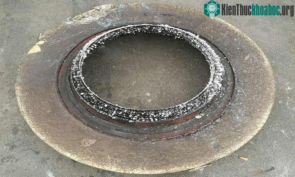 Mảnh vỡ rơi gần miệng hố là vòng tròn kim loại lớn có nhiều ký tự và chữ số trên bề mặt.