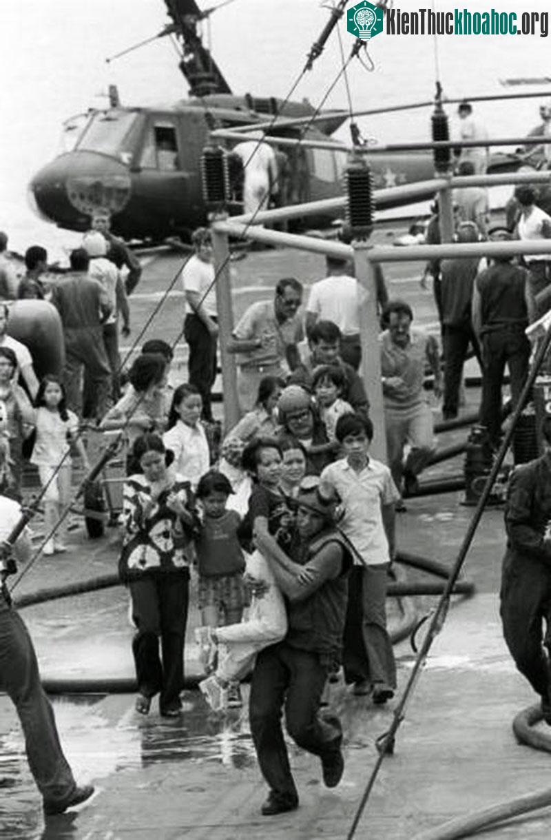 Phi công Mỹ bế một em bé đến nơi trú ẩn an toàn trên chiến hạm USS Blue Ridge sau khi chiếc trực thăng chở em cùng nhiều người khác va chạm trong lúc ...