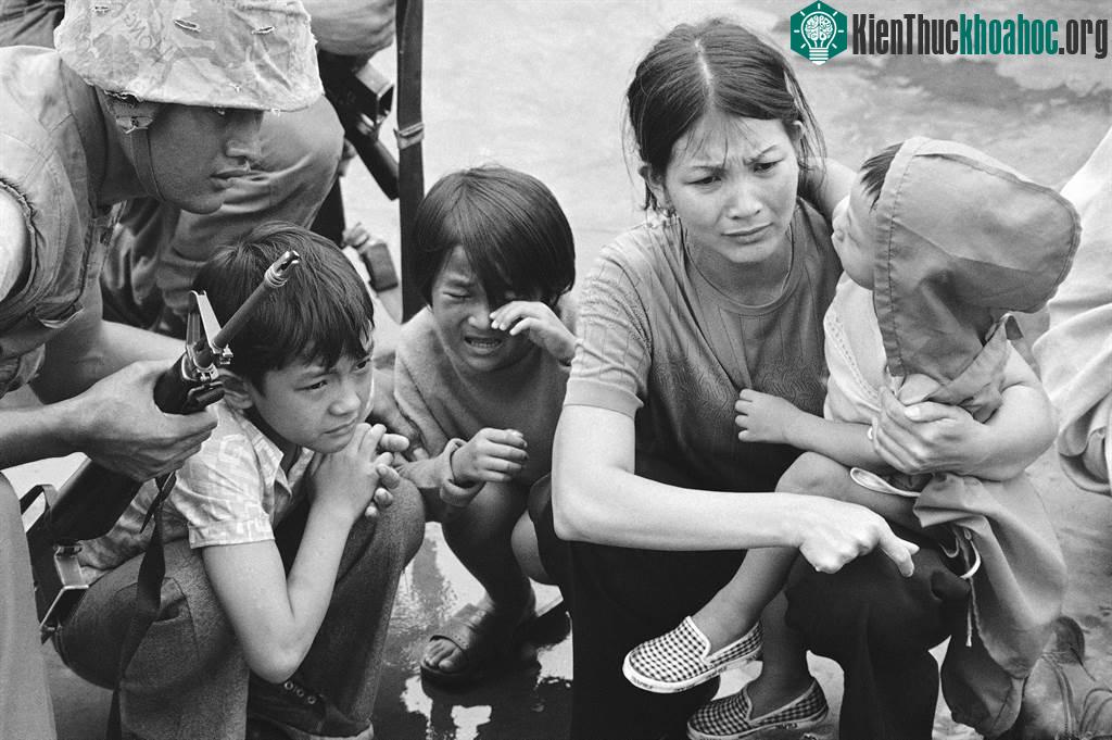 Một phụ nữ cùng ba người con chờ lên trực thăng của lính thủy đánh bộ Mỹ.