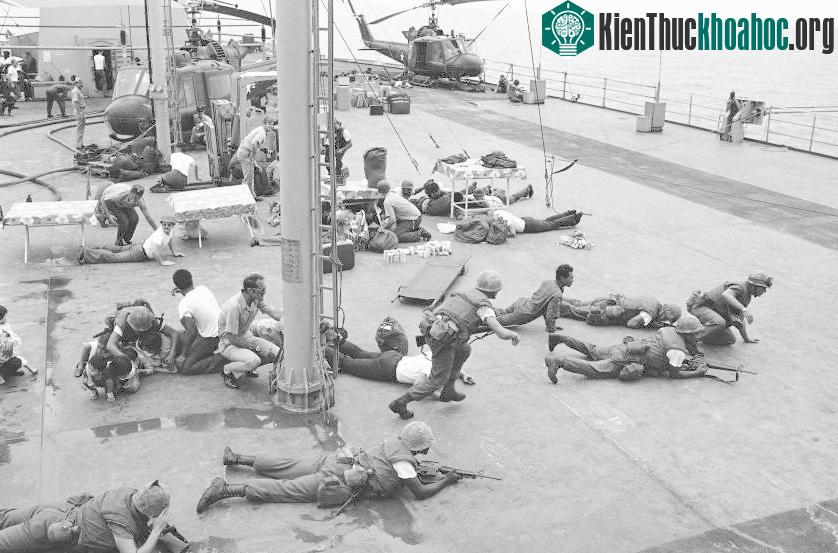 Lính thủy đánh bộ Mỹ nằm rạp trên boong chiến hạm USS Blue Ridge để tránh những mảnh vỡ kim loại văng ra từ một máy bay trực thăng khi nó hạ cánh và va chạm với một chiếc trực thăng khác.