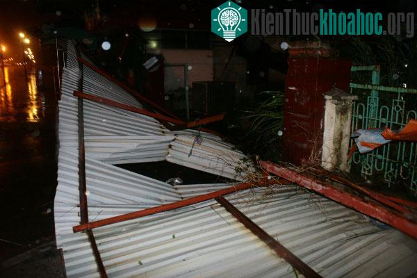 Một đoạn hàng rào tôn bị gió lớn quật xuống đường. (Ảnh: Bá Đô)