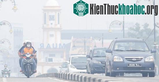 Người dân đeo khẩu trang đi trên đường phố khói mù dầy đặc ở Muar ngày 23/6 vừa qua. (Ảnh: AFP/TTXVN)