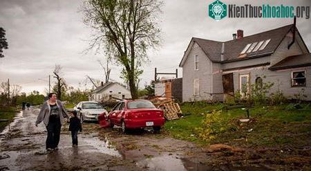 Một phụ nữ dắt con đi qua khu vực bị lốc xoáy tấn công tại Thurman, bang Iowa.