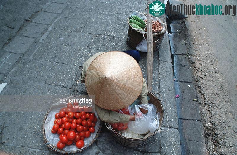 Một người phụ nữ bán rau quả rong bên vỉa hè.