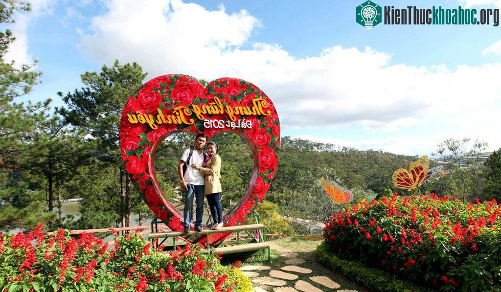Đôi bạn trẻ tranh thủ ghi hình lưu niệm tại vườn hoa có hình tượng biểu trưng cho tình yêu.