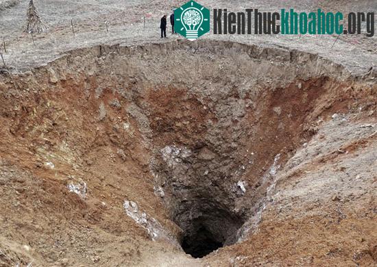 Người dân đứng cạnh một miệng hố có đường kính 24,9m ở một ngôi làng thuộc tỉnh Tứ Xuyên tháng 2/2013. Giới truyền thông địa phương đưa tin, hố hình thành sau khi mặt đất bị sụt lún trong vòng 6 ng...