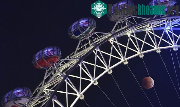 Siêu trăng máu ẩn hiện phía sau các cabin của vòng quay London Eye ở London, Anh. (Ảnh: Toby Melville/Reuters).
