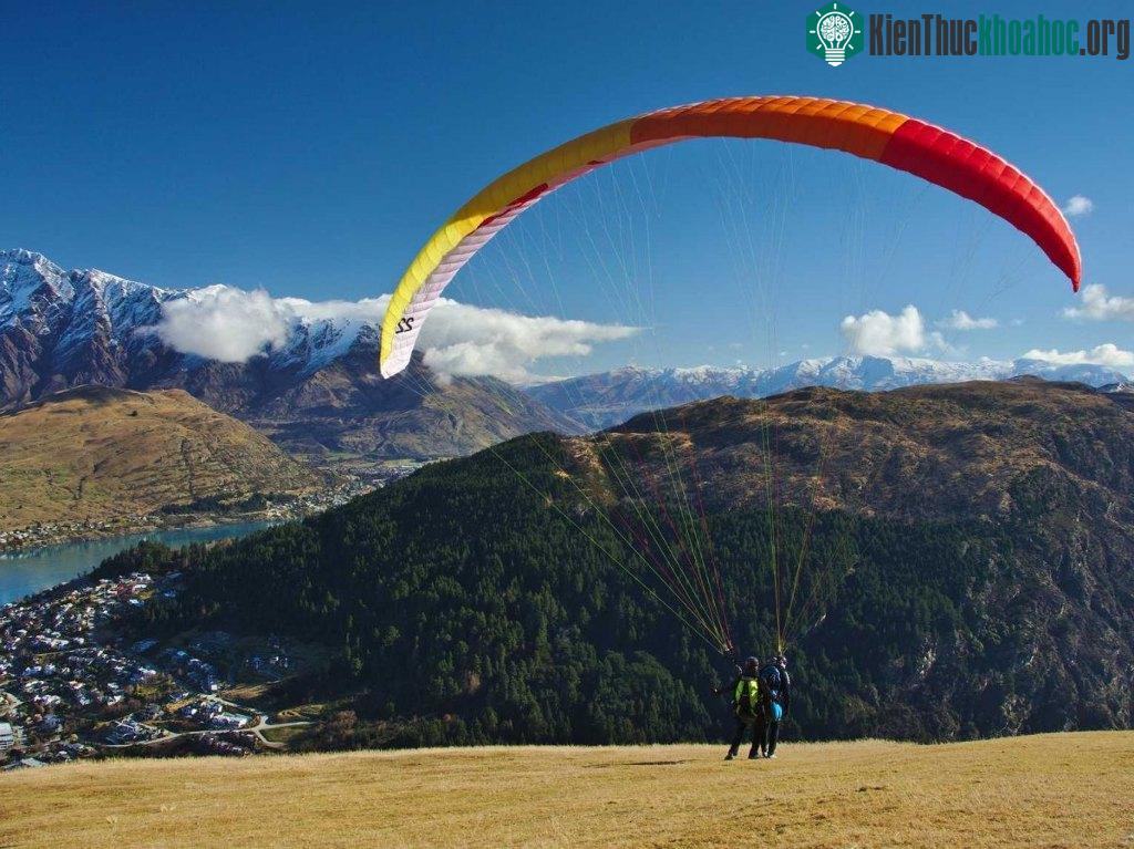 Chơi dù lượn trên các ngọn núi và ao nước bao quanh thành phố đẹp như tranh vẽ của Queenstown, New Zealand.