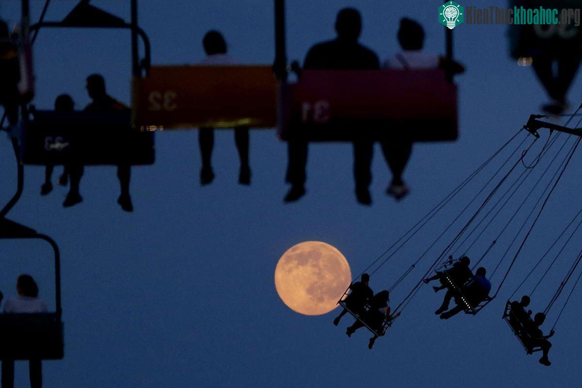 Trăng lên khi mọi người đang chơi đu quay ở State Fair Meadowlands, East Rutherford, New Jersey, 01/07/2015.