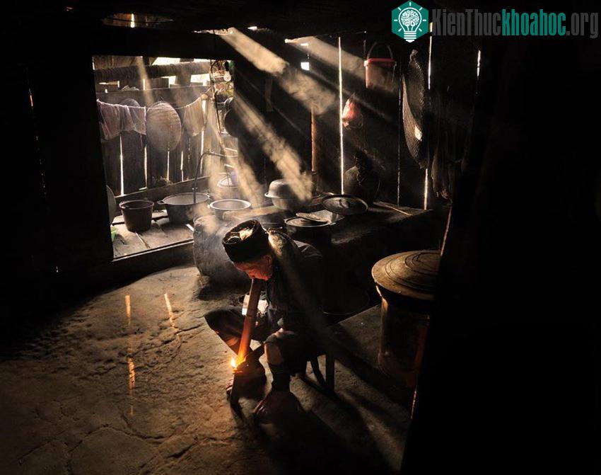 Một phụ nữ dân tộc H'Mong đang châm đóm hút thuốc lào