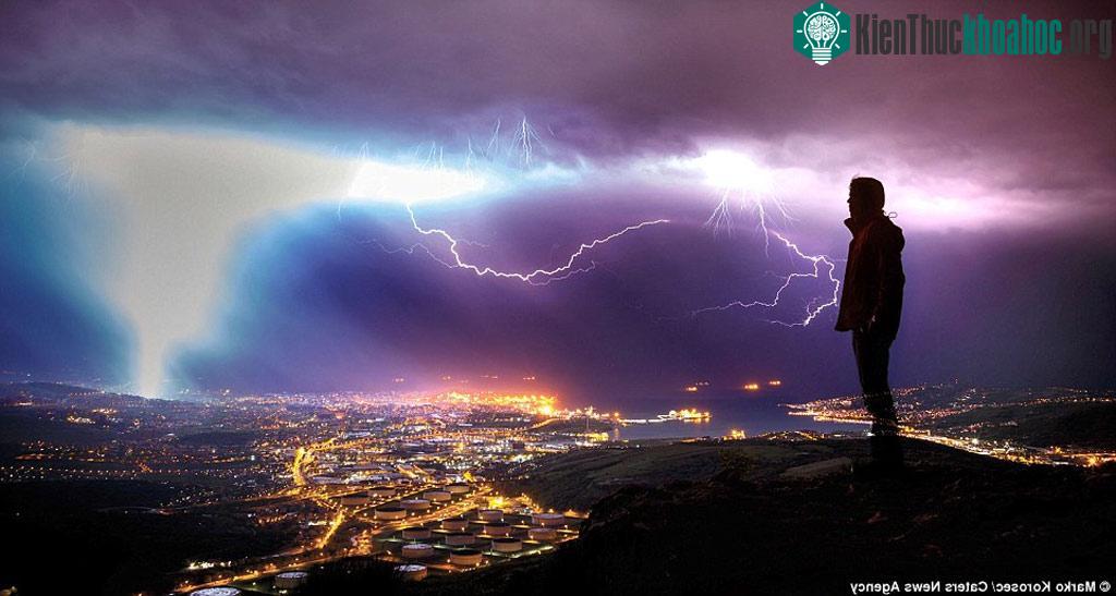 Du khách ngắm cảnh tượng sét đánh trong một cơn dông trên bầu trời thành phố Trieste, Italia.