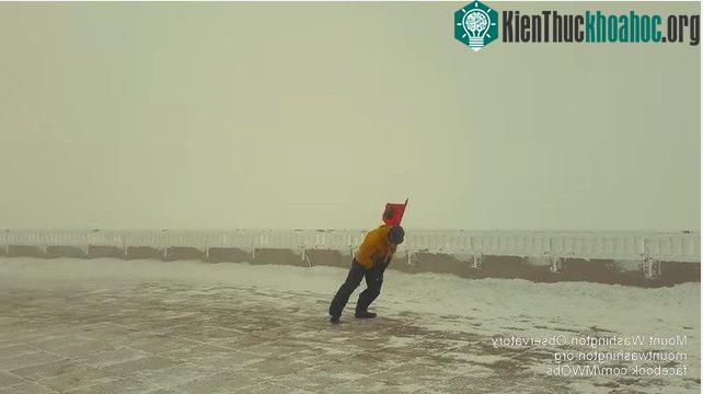 Nhà khoa học cầm chặt lá cờ màu cam và cúi thấp người tiến về phía trước.