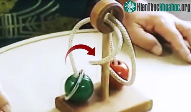 Thiết bị gồm trục gỗ, dây thừng, hai viên bi và một chiếc vòng. (Ảnh cắt từ clip).
