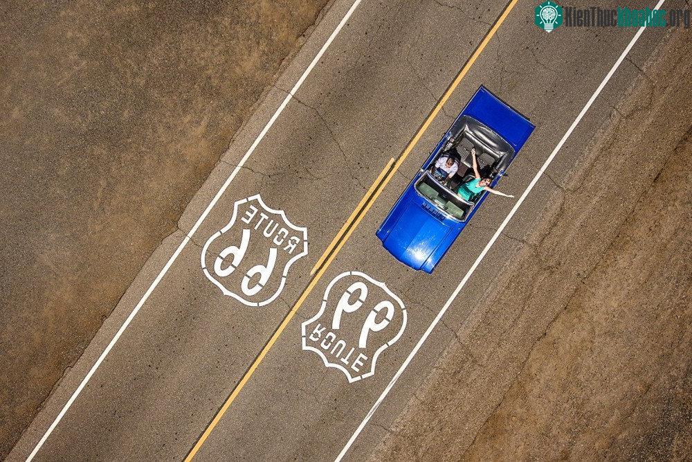 Cặp đôi ngồi trên chiếc Ford Mustang Convertible di chuyển dọc đường Route 66 ở Mỹ.