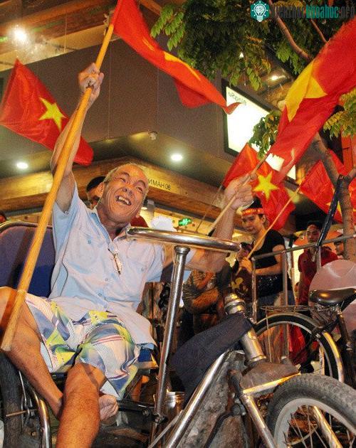 Tại giao lộ Pasteur - Hàm Nghi, cụ ông khuyết tất ngồi xe lăn cũng nhờ người nhà đưa ra đường vẫy cờ