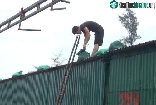 Người dân đưa cát lên mái nhà đề phòng gió lốc. (Ảnh: Nguyễn Hải).