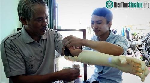 Dết thử nghiệm bàn tay robot với ông Minh. (Ảnh: Thạch Thảo).