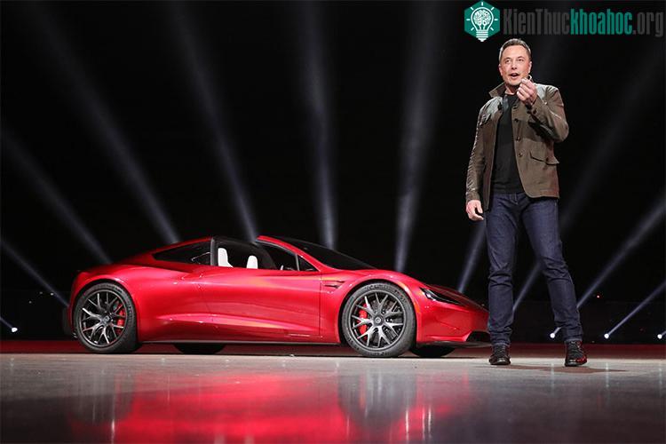 Tỷ phú Elon Musk, CEO SpaceX, đứng bên cạnh chiếc xe điện Tesla Roadster mui trần màu đỏ.