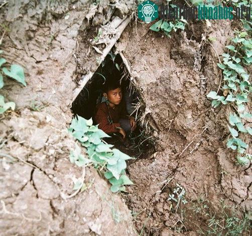 Em bé ngồi trong hầm tránh bom.