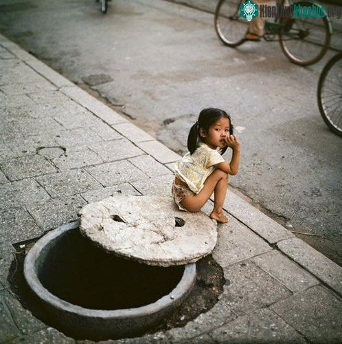 Bé gái ngồi bên miệng hầm trú ẩn.