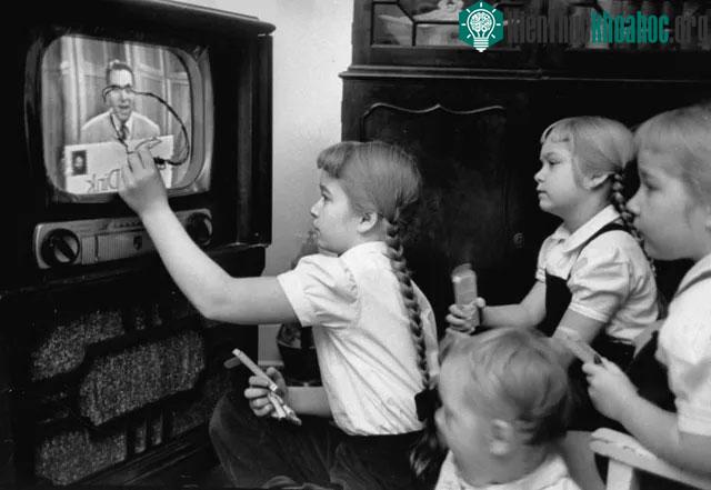 Một cô bé đang tập trung vẽ lên màn hình TV