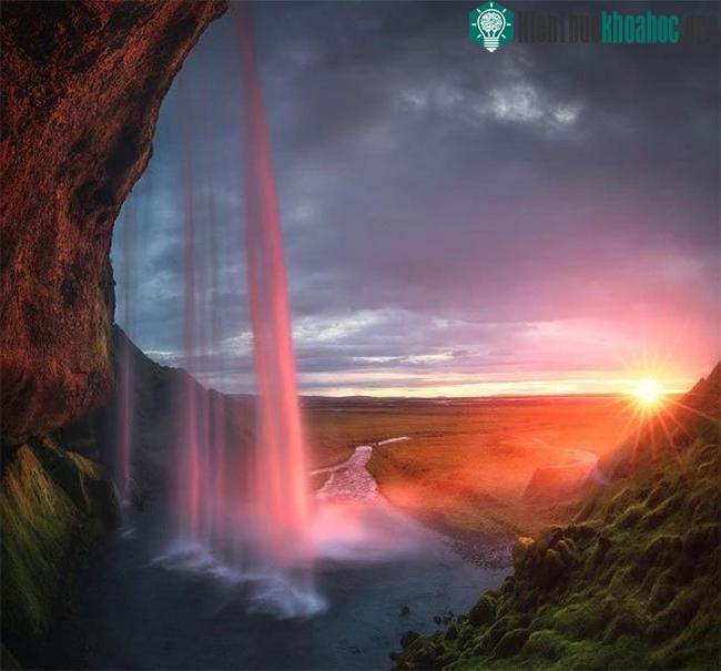 Hoàng hôn nửa đêm phản chiếu trong một thác nước ở Iceland