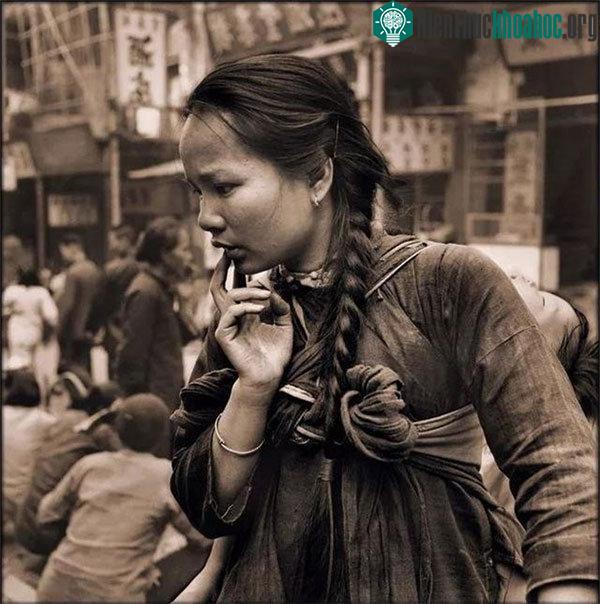 Một người mẹ trẻ địu con đang xem một quầy hàng bên đường.