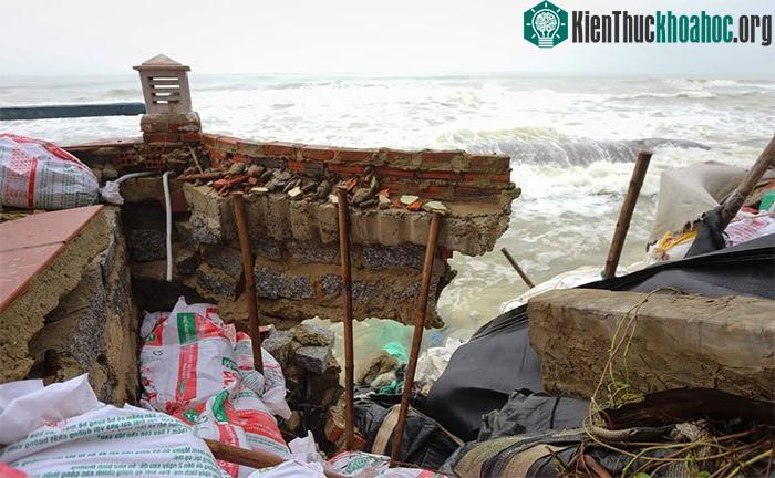 Một đoạn tường xây bằng đá, gạch, xi măng bị sóng đánh sập phía dưới